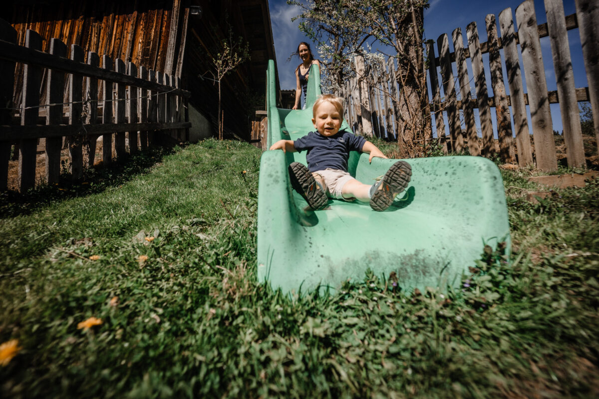 Kleinkind rutscht auf dem Spielplatz am Bauernhof