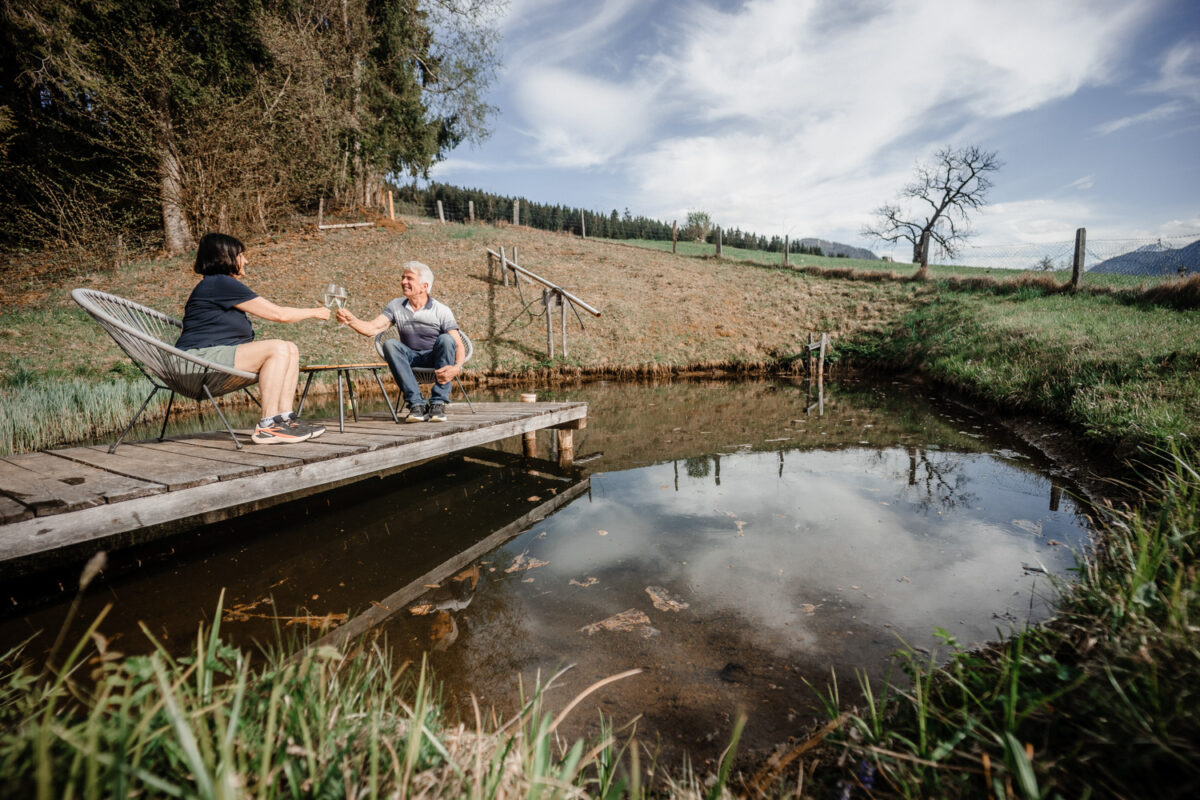 Kinder sitzen am kleinen Naturteich