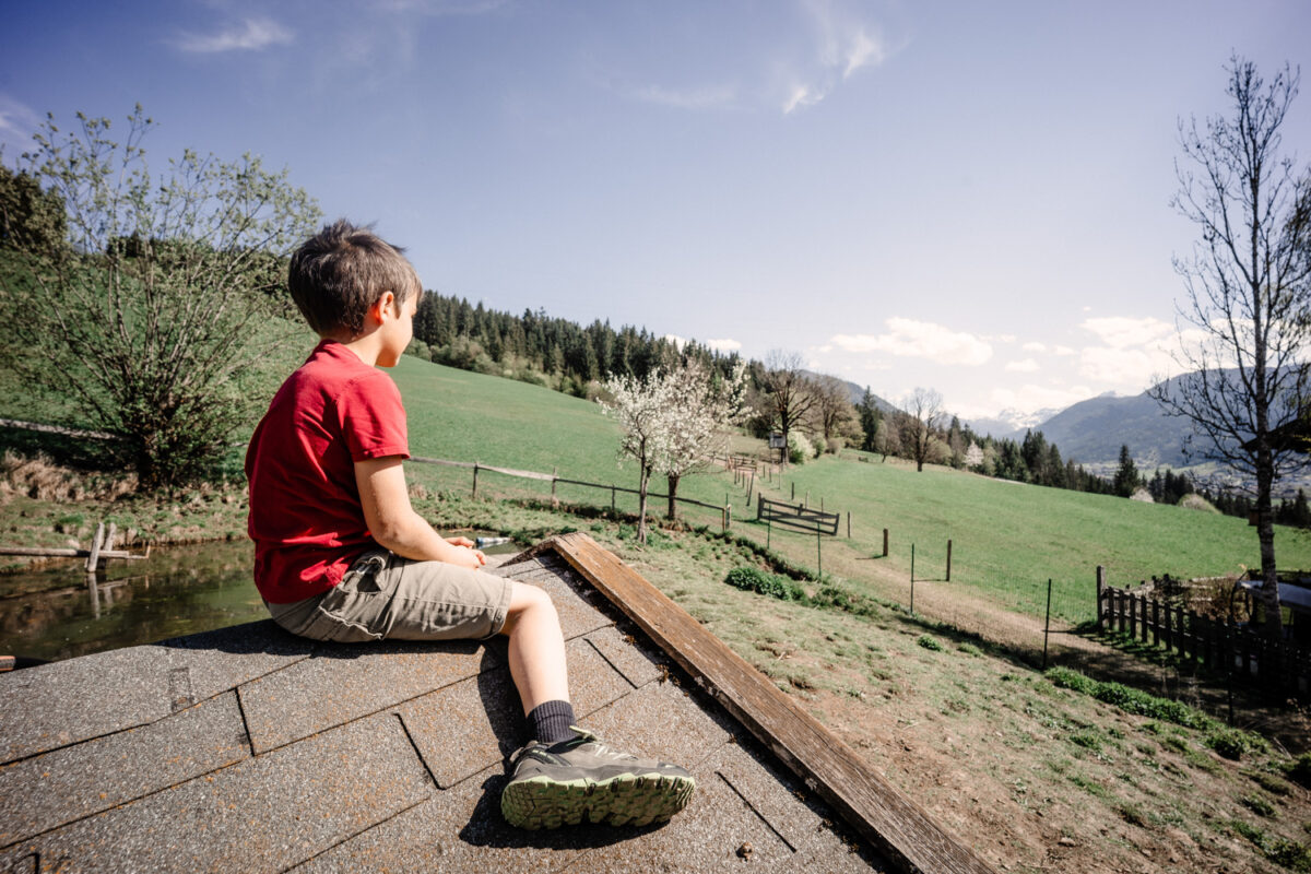 Junge genießt die Aussicht über die Wiesen bei Flachau