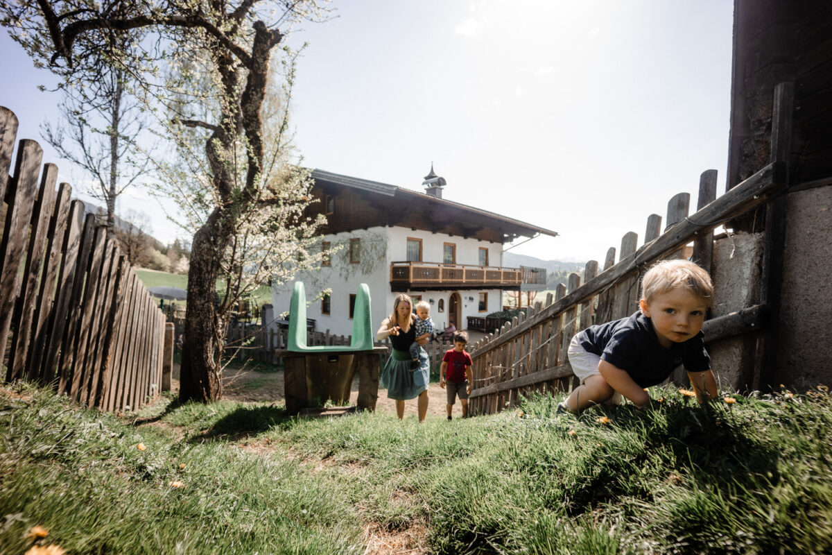 Kinder spielen auf der Wiese neben dem Bauernhaus