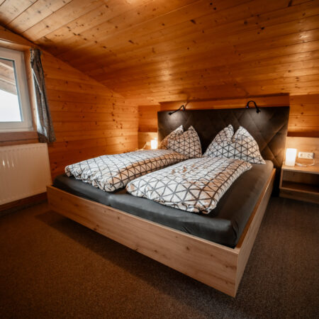Doppelbett im gemütlichen Schlafzimmer mit Holzvertäfelung