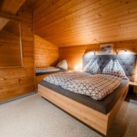 Schlafzimmer mit Doppelbett und warmer Holzvertäfelung