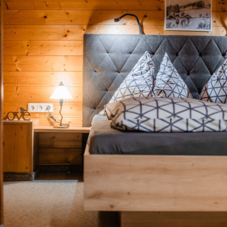 Doppelbett mit gepolstertem Kopfteil im Holzschlafzimmer