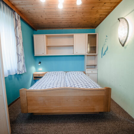 Schlafzimmer mit Doppelbett und hellblauer Wand