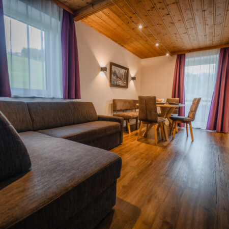 Wohnzimmer mit Sofa, Esstisch und Zugang zum Balkon