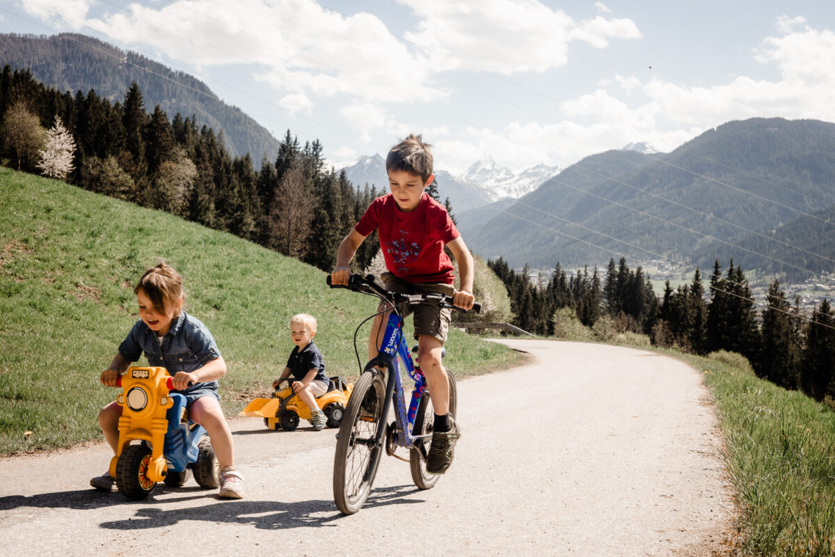 Kinder fahren mit Tretfahrzeugen auf dem Bauernhofweg